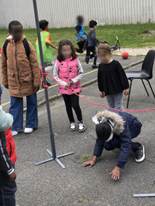 enfant les yeux bandés passant sous une corde tendue entre deux poteaux